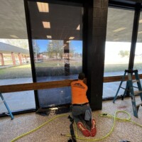 Worker applying window tinting to building | TN Film Solutions